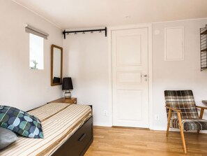A bedroom with a bed, a chair, a wardrobe, a mirror, and a door. - Solgläntan by Interhome (Halmstad)
