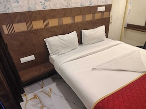 A bed with a wooden headboard, white bedding, and a red quilted blanket. - Hotel city grand inn (Coimbatore)