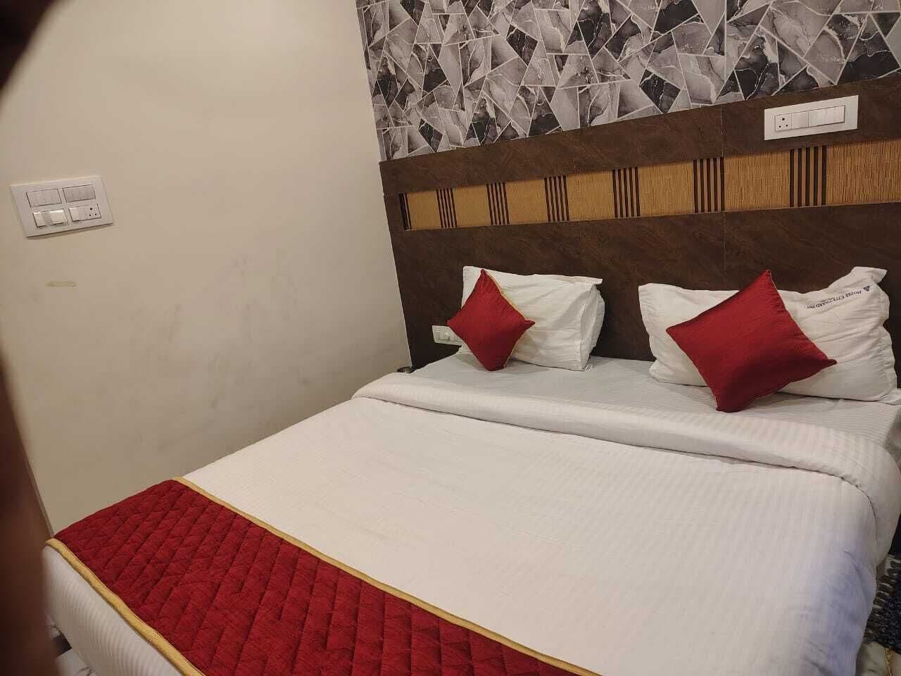 Une chambre d’hôtel avec un lit, une couvre-lit rouge matelassée et une tête de lit ornée d’un motif géométrique en carreaux.