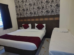 A hotel room with a large bed, a smaller bed, and a patterned wall. - Hotel city grand inn (Coimbatore)