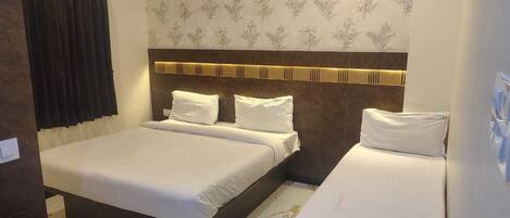 A hotel room with a large bed, a smaller bed, and a bedside table with a remote control.
