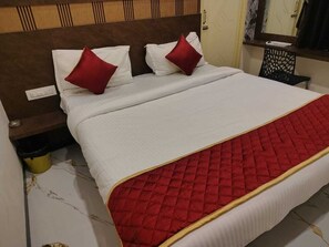 Una cama bien hecha con colcha acolchada roja y almohadas blancas.