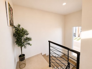 Eine Treppe mit Metallgeländer, einem Blumentopf und einem gerahmten Bild an der Wand.