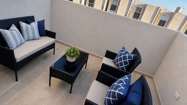 Eine Dachterrasse mit einer Sofagruppe, einem Couchtisch und gestreiften Kissen.