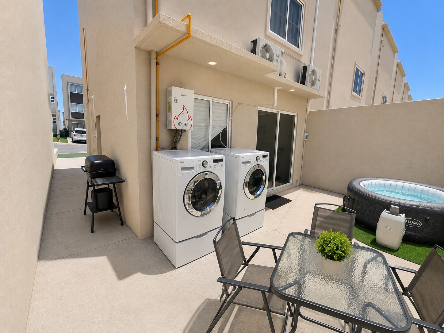 Un área de lavandería con dos lavadoras, una parrilla para barbacoa y un jacuzzi.