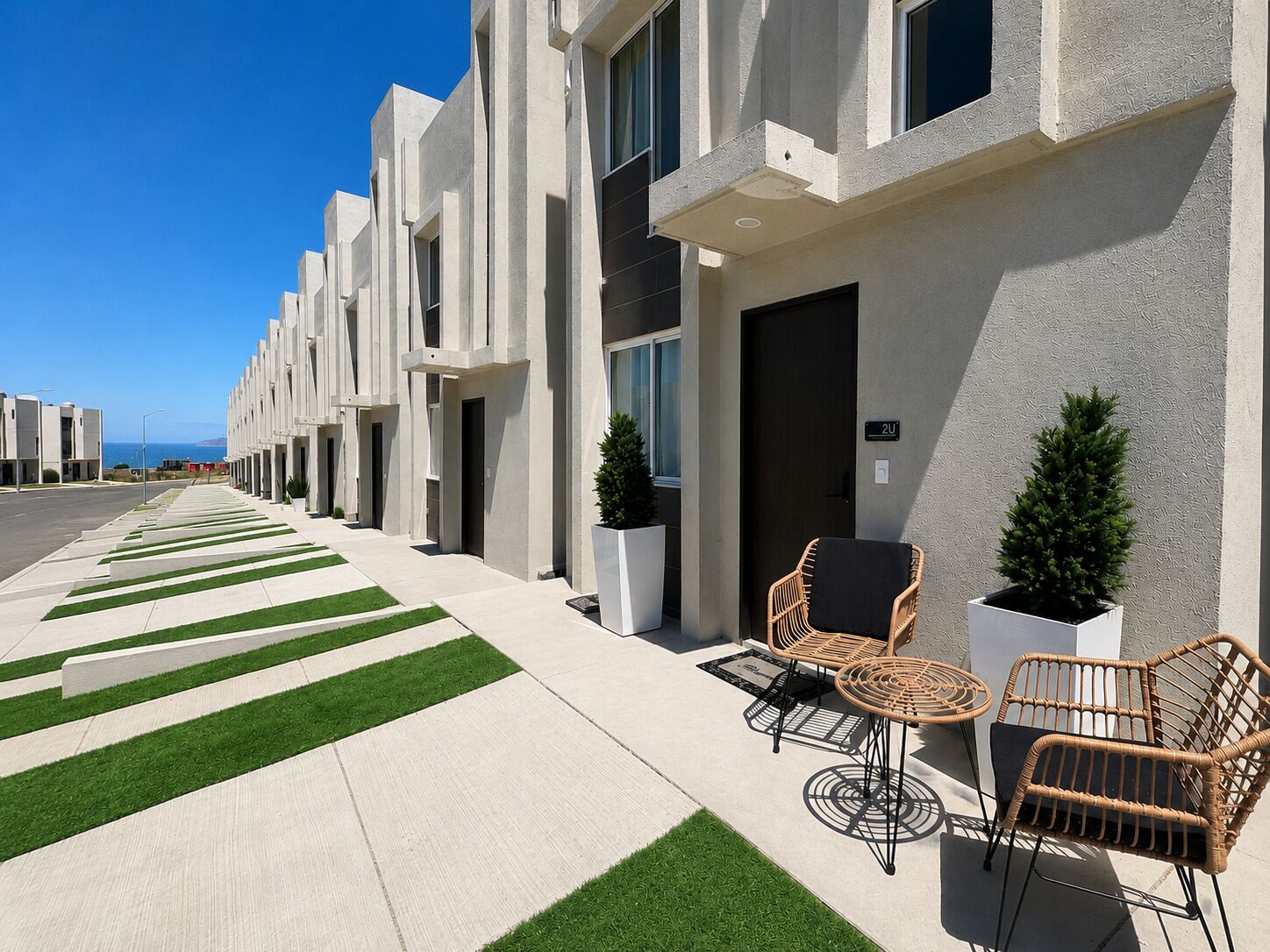 A modern building with a clean, geometric facade, a well-maintained lawn, and outdoor seating area with wicker chairs.
