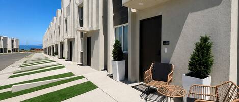 A modern building with a clean, geometric facade, a well-maintained lawn, and outdoor seating area with wicker chairs.