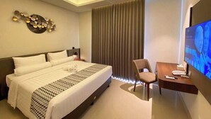 A hotel room with a bed, a desk, a television, and a decorative wall piece.