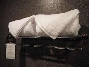 A folded white towel on a metal towel rack with a tag attached.