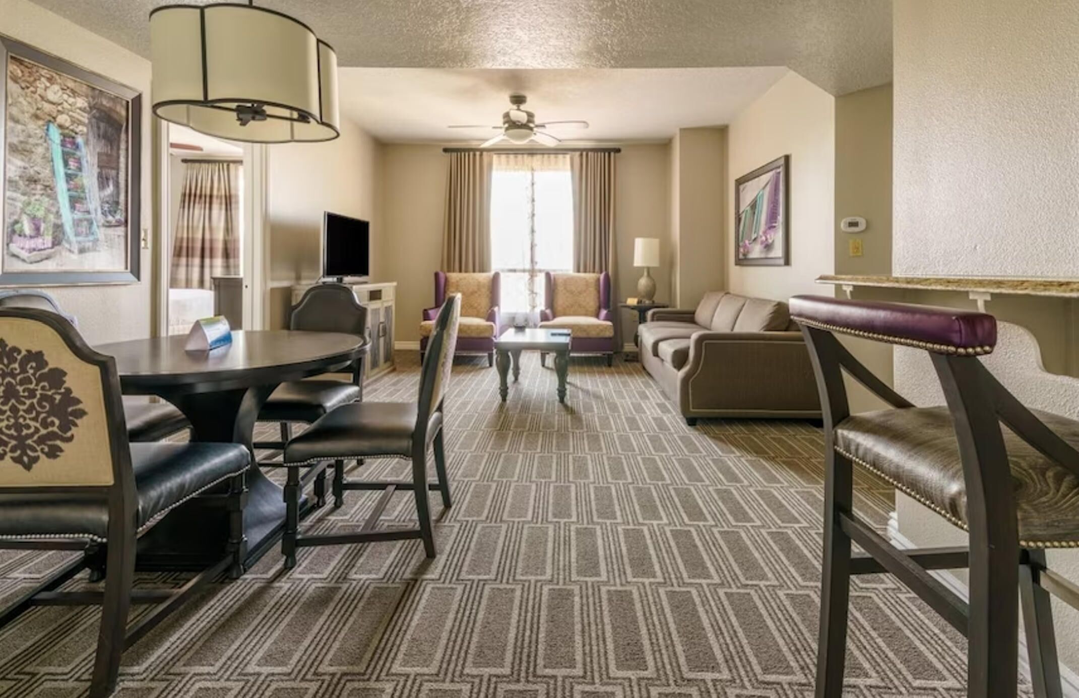 Une chambre d’hôtel équipée d’une table à manger, de deux canapés, d’une table basse et d’un ventilateur de plafond.