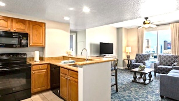 A compact living space with a kitchenette, a flat-screen TV, a sofa, and a dining area.