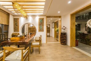 A dining area with a long wooden table, chairs, and a hanging light fixture. - Youdu Inn (Dali City)