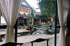 A traditional courtyard with a water feature, a wooden bench, and a building with traditional architecture. - Youdu Inn (Dali City)