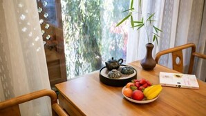 A wooden table with a teapot, a bowl of fruit, and a book. - Youdu Inn (Dali City)
