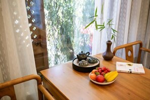 A wooden table with a teapot, a bowl of fruit, and a book. - Youdu Inn (Dali City)