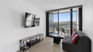 Ein modernes Wohnzimmer mit großem Fenster, Flachbildfernseher, Sofa und Couchtisch.