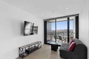 Ein modernes Wohnzimmer mit großem Fenster, Flachbildfernseher, Sofa und Couchtisch.