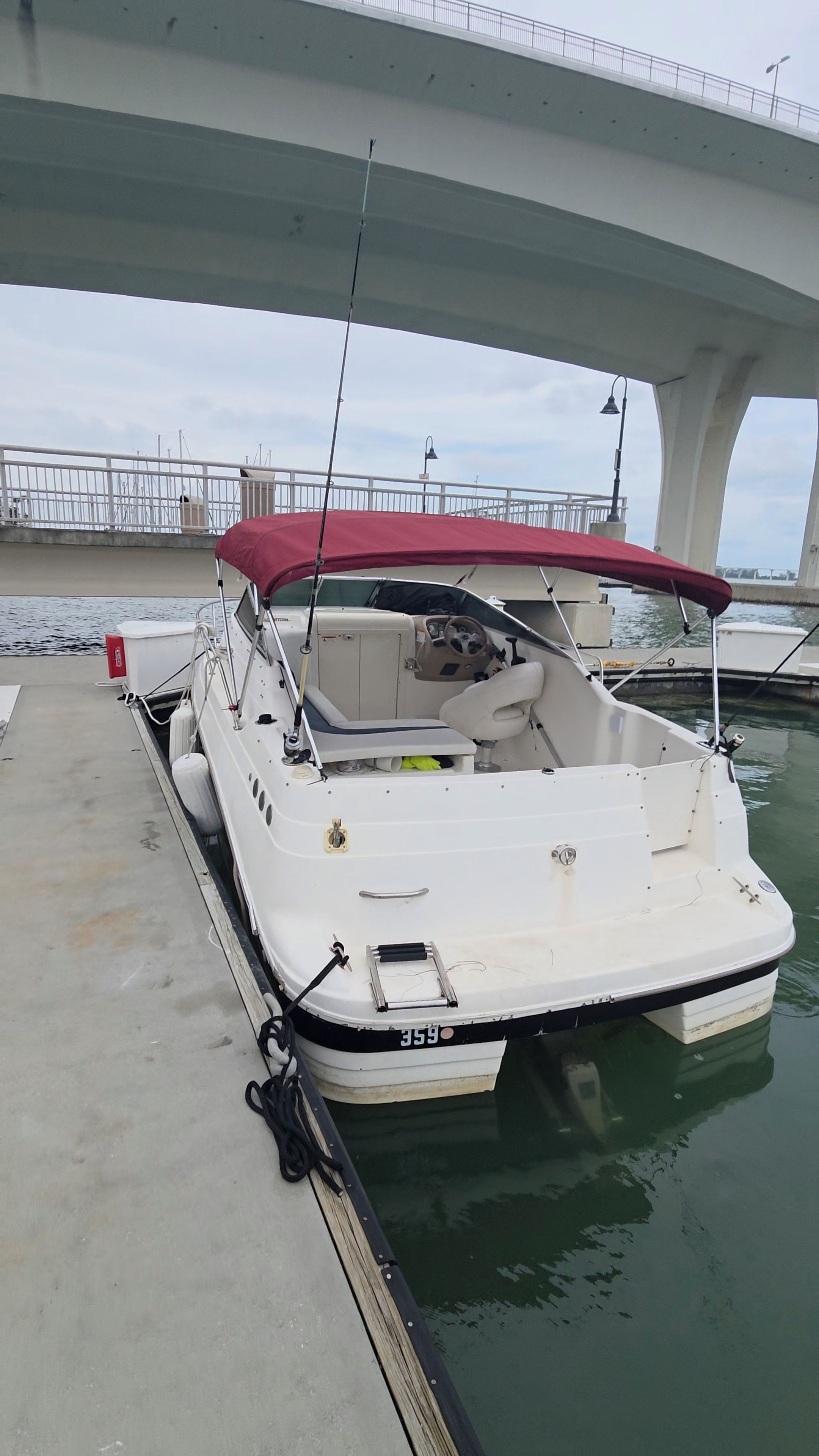 A boat docked at a pier with a bridge in the background.