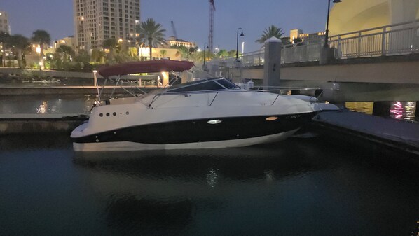 A boat docked at a marina with a cityscape in the background.