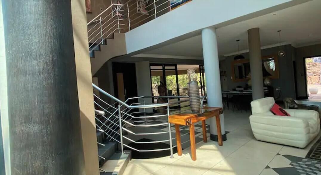 Um interior com vários níveis, incluindo uma escadaria, área de refeições e espaço para sentar.