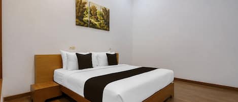 Une chambre à coucher avec un lit en bois, du linge de lit blanc, une table de chevet et un tableau accroché au mur.