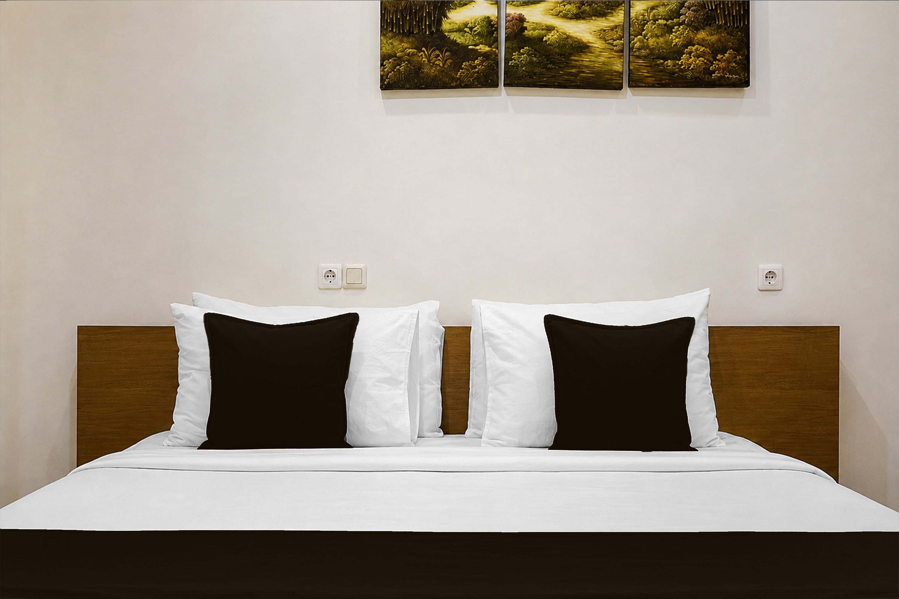 Une chambre d’hôtel avec un lit, deux oreillers blancs, une tête de lit marron foncé et un tableau accroché au mur.