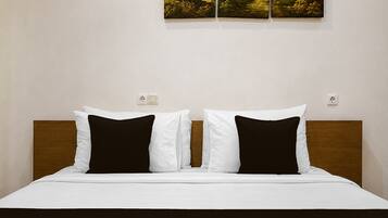 Une chambre d’hôtel avec un lit, deux oreillers blancs, une tête de lit marron foncé et un tableau accroché au mur.