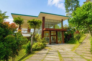 A modern house with a glass facade, a covered porch, and a stone pathway leading to the entrance.