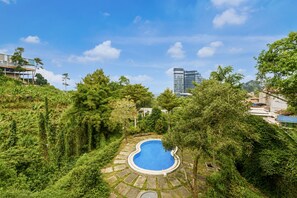 A swimming pool surrounded by lush greenery, with a modern building in the background.