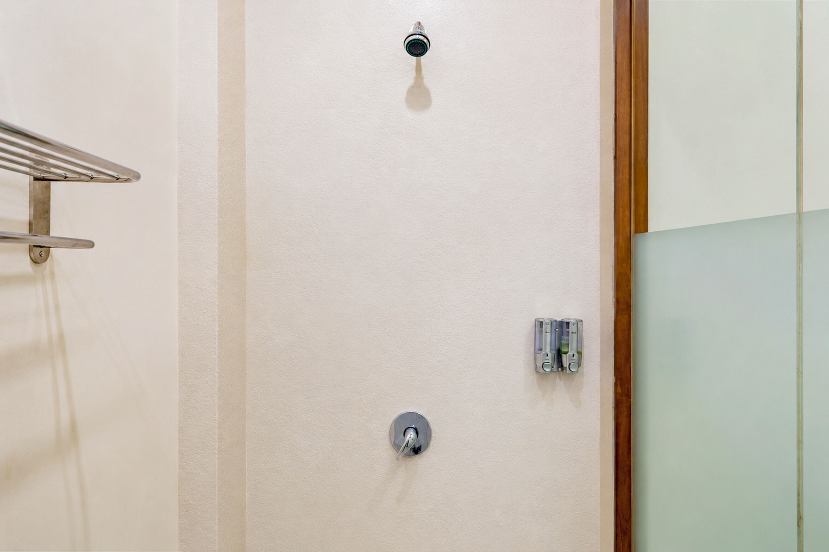 Ein Badezimmer mit Handtuchhalter, Duscharmatur und Glasabtrennung.