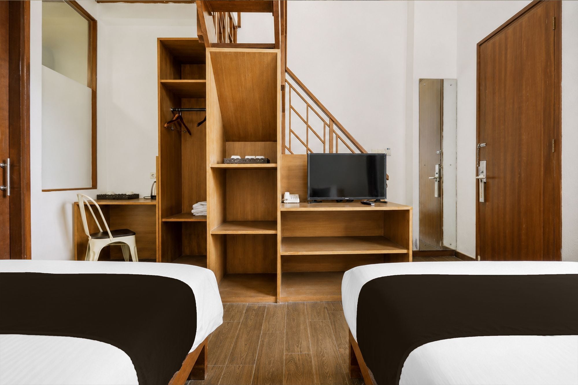 Habitación de hotel con dos camas, una escalera de madera, un televisor y un escritorio pequeño.