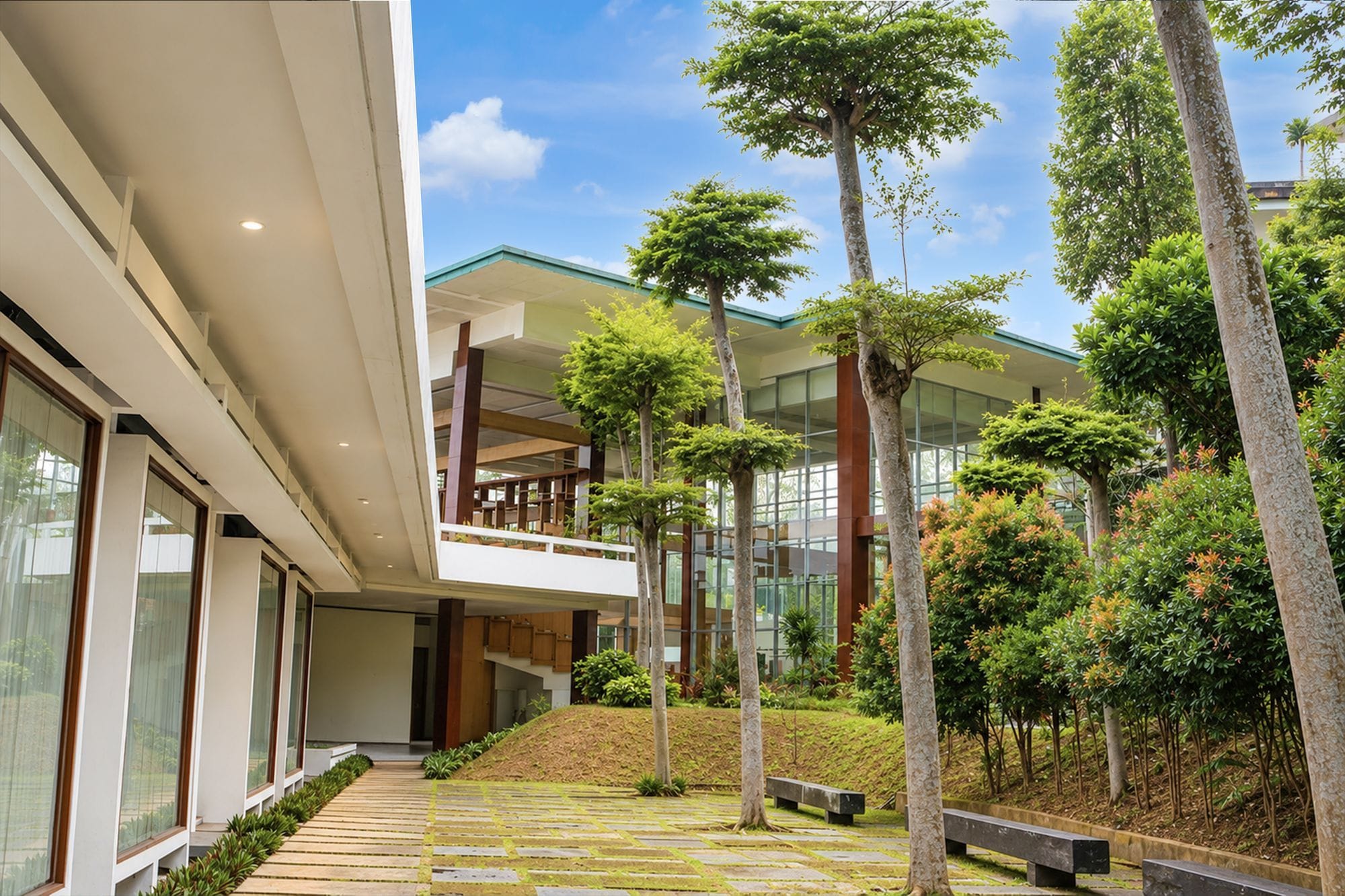 A modern building with a glass facade, a central courtyard with trees, and a staircase leading to an upper level.