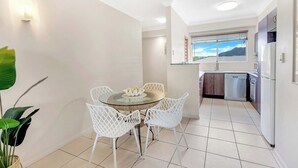 Uma cozinha moderna com armários brancos, máquina de lavar louça embutida e janela com vista para o exterior.