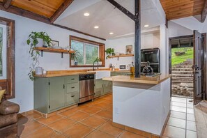Eine Küche mit Geschirrspüler, Backofen und integriertem Herd. Über der Spüle befindet sich ein Fenster und eine Tür führt nach draußen.