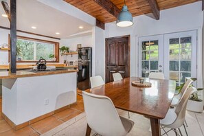 Une cuisine moderne avec un îlot en bois, des chaises blanches et une table à manger.
