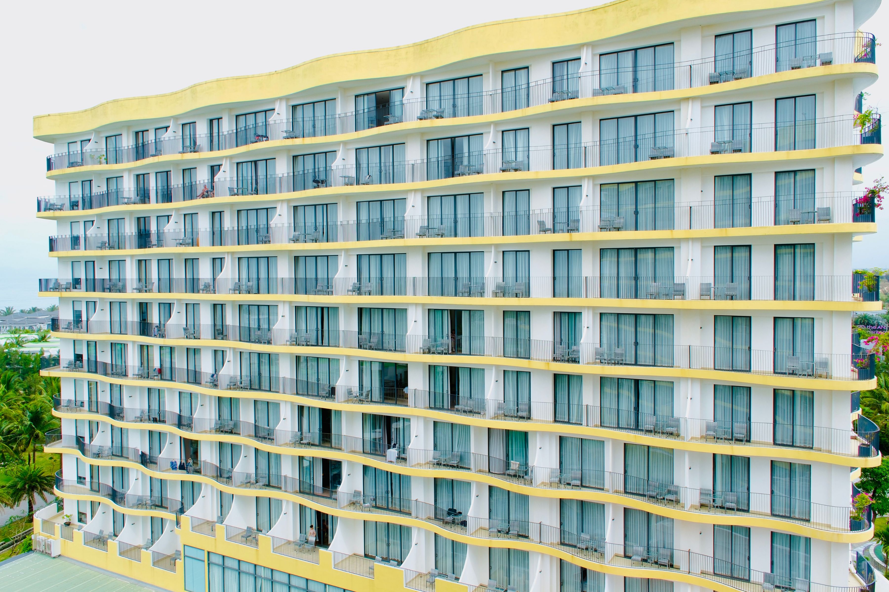 A multi-story hotel with balconies and large windows.
