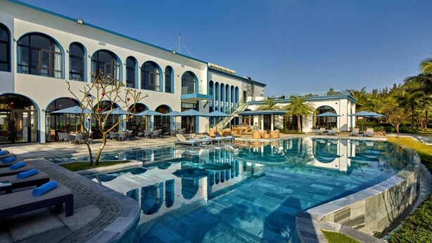 A hotel with a large pool, outdoor seating, and a modern architectural design. - Walk to Beach| lovely AP with pool for honeymoon (Da Nang)