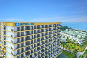 A multi-story hotel with a prominent 'WYNDHAM' sign, featuring balconies and a view of a beach resort. - Walk to Beach| lovely AP with pool for honeymoon (Da Nang)
