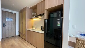 A modern kitchen with wooden cabinets, a black refrigerator, and a stainless steel sink. - Walk to Beach| lovely AP with pool for honeymoon (Da Nang)