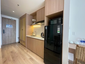 A modern kitchen with wooden cabinets, a black refrigerator, and a stainless steel sink. - Walk to Beach| lovely AP with pool for honeymoon (Da Nang)
