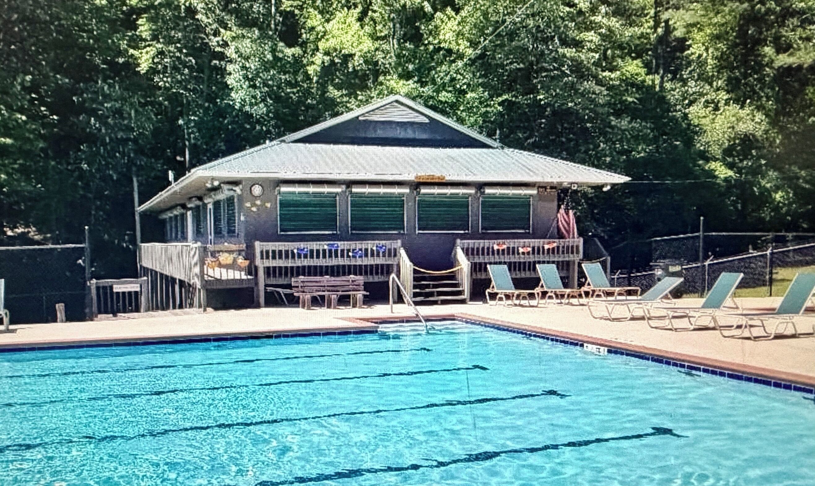 A swimming pool with lounge chairs and a covered area with a roof.
