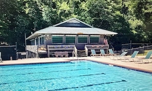 A swimming pool with lounge chairs and a covered area with a roof. - Charming Cabin in the clouds with hot tub, screen porch and fireplace (Ellijay)
