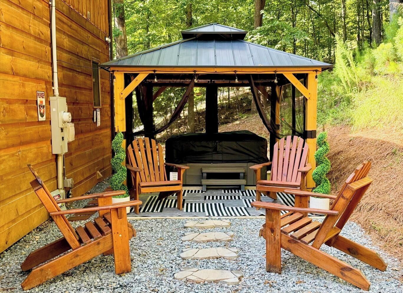 Un gazebo in legno con tetto nero e due poltrone Adirondack.