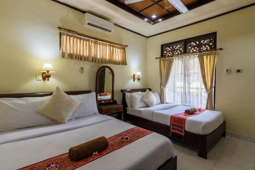 A hotel room with two beds, a large mirror, and a window with curtains.