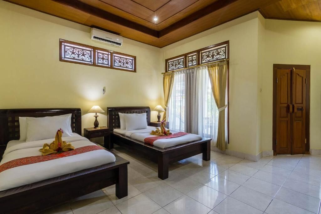 A hotel room with two beds, a wooden ceiling, and a large window with curtains.