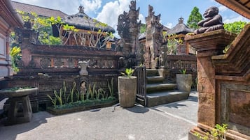 Ein Innenhof mit traditioneller Architektur, darunter Steinfiguren und ein Gebäude mit Strohdach.
