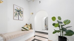 A clean, modern hallway with a bench, a potted plant, and a framed artwork on the wall.