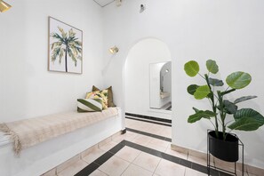 A clean, modern hallway with a bench, a potted plant, and a framed artwork on the wall.