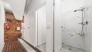 A corridor with a brick wall, white doors, and a shower area with marble tiles.