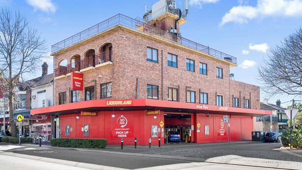 A red-brick building with a flat roof and a balcony on the second floor.